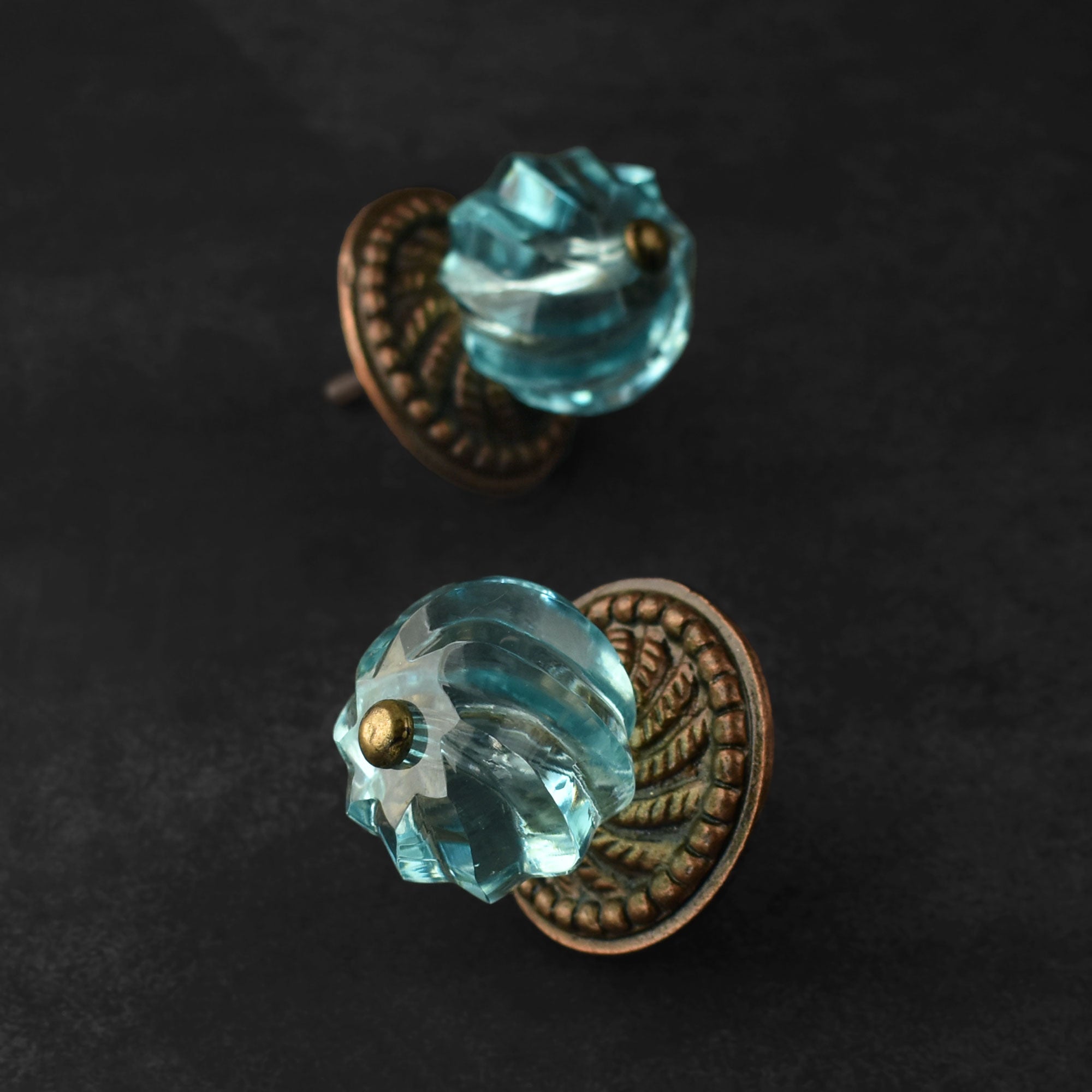 blue glass door knobs with bronze metal bases on a dark background