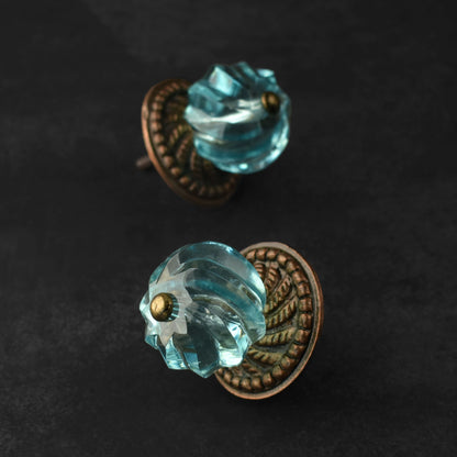 blue glass door knobs with bronze metal bases on a dark background